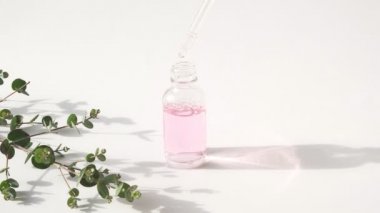 Yağlı damlalar düşer. Doğal kozmetik yağlı damlatan cam şişe. Kozmetik pipetli bir şişe. Nemlendirme önleyici ürün. Deri ve vücut bakımı. Pembe yağ ürünü. Parfüm