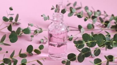 Doğal kozmetik yağlı damlatan cam şişe. Kozmetik pipetli bir şişe. Doğal bitkiler ve bitkiler güzellik ürünü. Cilt bakımı. Parfüm. Pembe yağ damlaları düşer