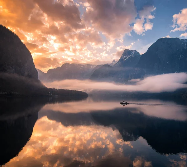 Avusturya Hallstatt köyünün bir gölde aracılığıyla şafak güneş ışınlarının yelken bir feribot