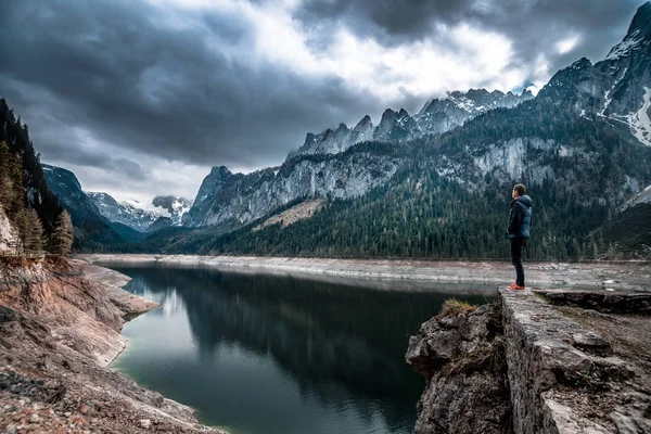 dağ doruklarına bir arka plan üzerinde göl kenarında duran adam. 