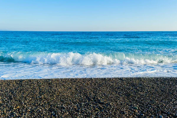 Olas rompiendo en una playa pedregosa, formando aerosoles —  Fotos de Stock