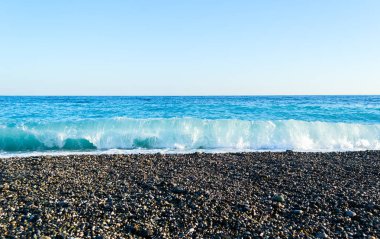 Taşlı bir kumsalda kırma dalgalar spreyler şekillendirme