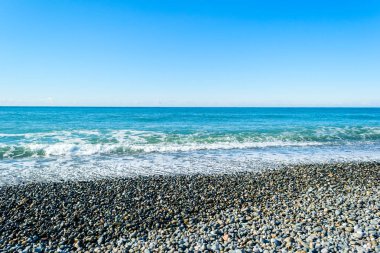 Taşlı bir kumsalda kırma dalgalar spreyler şekillendirme