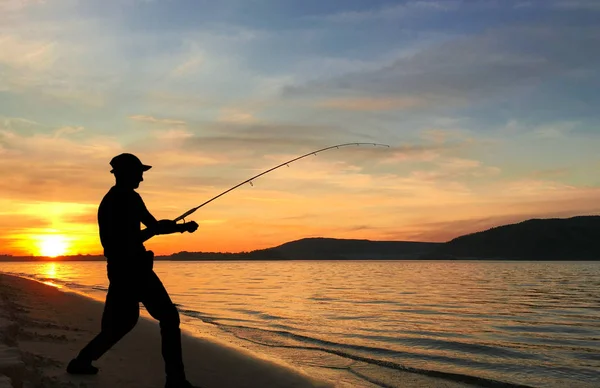 Junger Mann angelt bei Sonnenuntergang — Stockfoto