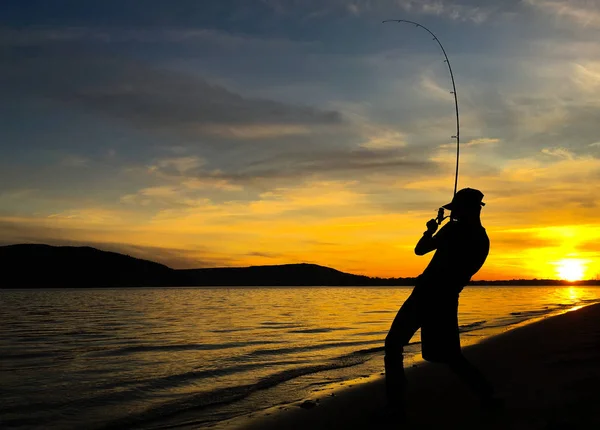 Молодой человек рыбачит на закате — стоковое фото