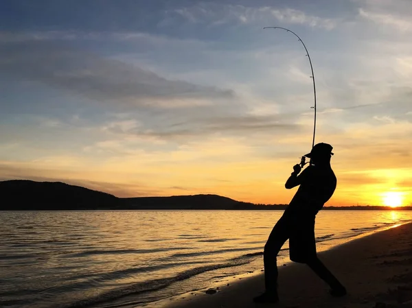 Молодой человек рыбачит на закате — стоковое фото