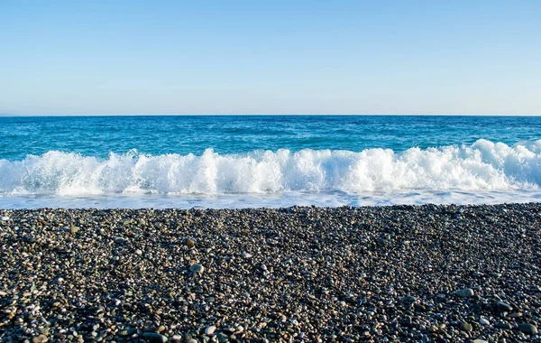 Волны ломаются на каменистом пляже, образуя спреи — стоковое фото