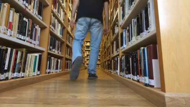 Hombre de mediana edad busca y recoge un libro en una biblioteca — Vídeos de Stock