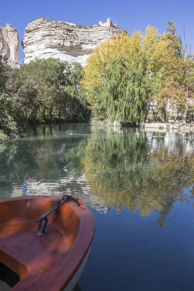 Jucar River, boat of recreation in small lagoon in the central part of the town, at the top of mountain limestone is situated castle of Almohad origin of the century XII, Alcala del Jucar, Spain — стоковое фото