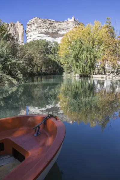 Jucar River, boat of recreation in small lagoon in the central part of the town, at the top of mountain limestone is situated castle of Almohad origin of the century XII, Alcala del Jucar, Spain — стоковое фото