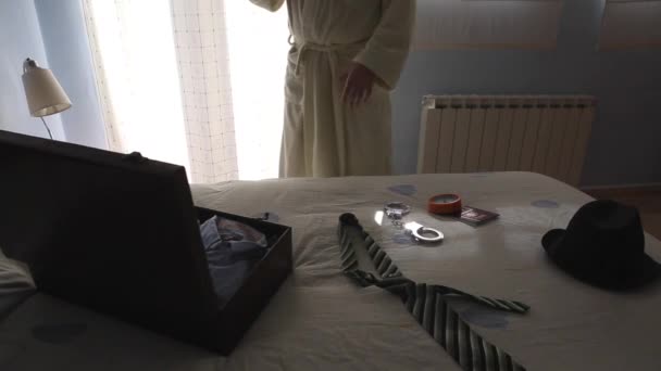 Мужчина в халате в отеле разговаривает по телефону рядом с кроватью — стоковое видео