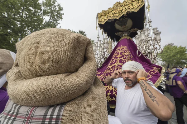 Gruppe starker Männer, die spanische "costaleros" genannt werden und den Thron mit einem Sack auf dem Kopf tragen, während der Buße am Heiligen Freitag, aufgenommen in Linares, Andalusien, Spanien — Stockfoto