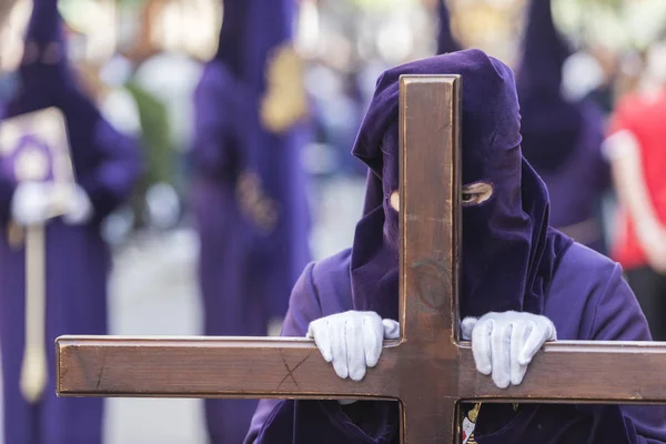 Penitent dressed in purple tunic of velvet resting on wooden cross during atonement station on Holy Week, Take in Linares, Andalusia, Spain — Stock Photo, Image