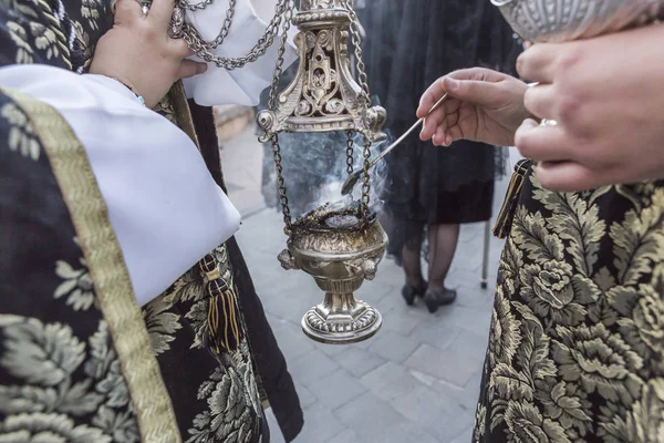 Крупный план алтарных серверов, жгущих благовония в кадильнице во время станции покаяния в воскресенье Воскресения Христова, принимать в Линаресе, Андалусия, Испания — стоковое фото