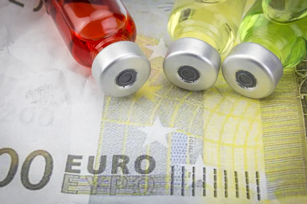 Vials with different substances over euros, concept of copayment — Stock Photo, Image