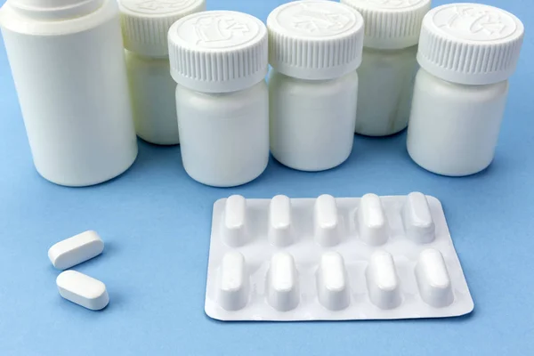 Pillen wit met witte tabletten van verschillende typen boten op blauwe achtergrond — Stockfoto