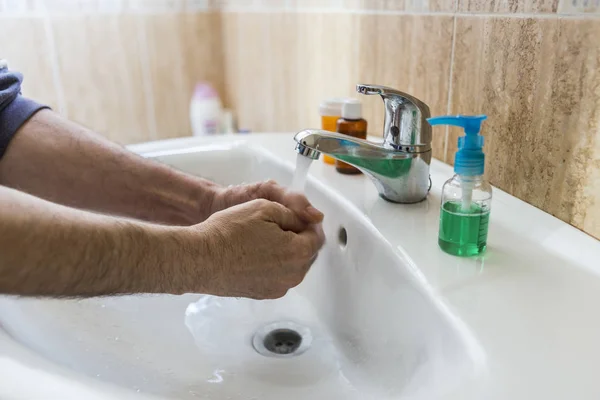 Closeup of a young caucasian man washing his hands with soap in the sink of a bathroom — Stock Photo, Image