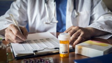 Doktor, tıbbi muayene ya da reçete üzerine hasta notları yazıyor.