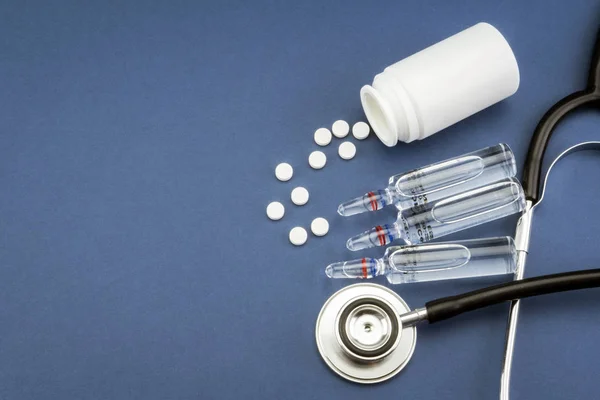 Estetoscópio, comprimidos, frascos para injetáveis na sala médica em fundo azul vista superior mockup — Fotografia de Stock