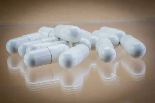 Veel medicijnen witte pillen capsules op bruine achtergrond — Stockfoto