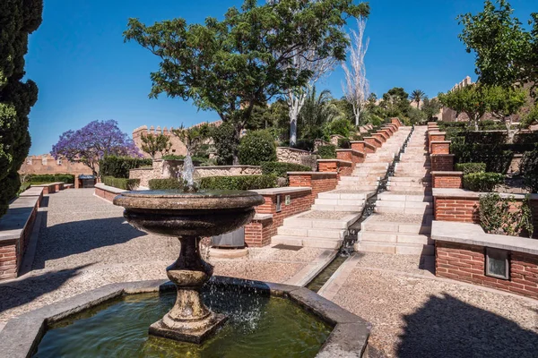 Fortaleza morisca medieval Alcazaba en Almería, Acceso a la Alcazaba con jardines y árboles de diferentes especies, fuente y escaleras de entrada de agua de plomo a lo largo, tomar en Almería, Andalucía, España — Foto de Stock