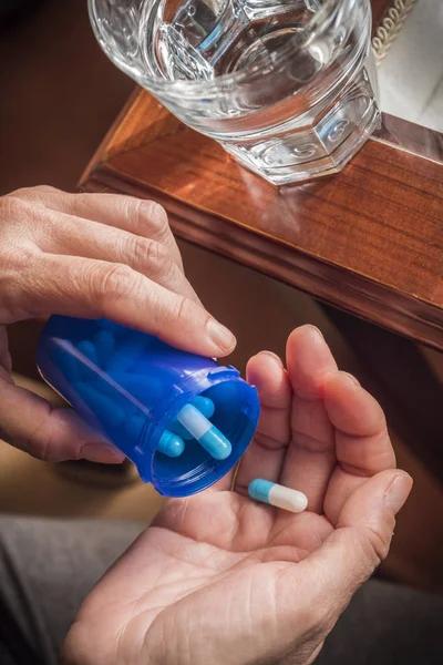 Women take white and blue capsule with left hand from a blue bottle