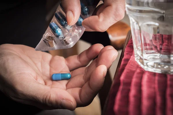 Women take blue capsule with left hand from a container pills — Stock Photo, Image