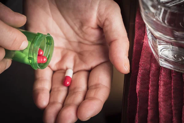 Vrouwen nemen witte en rode capsule met rechterhand van een groene fles — Stockfoto