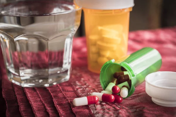 Белые и красные таблетки, проливающиеся из открытой зеленой бутылки — стоковое фото