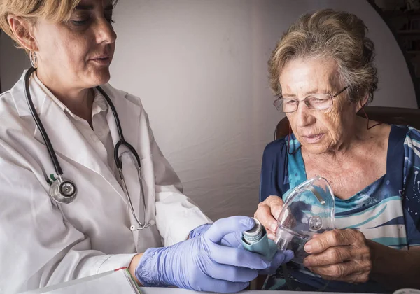 Doktor yaşlı kadına açıklar nasıl ventimask inhalasyon eğitim çalışır, Endülüs, İspanya