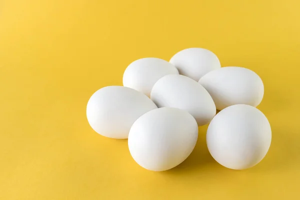 Siedem biały jaja kurze na białym tle na żółtym tle — Zdjęcie stockowe