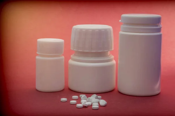 Pillen boten wit met witte tabletten van verschillende typen geïsoleerd op rode achtergrond — Stockfoto