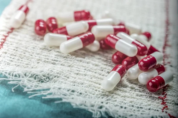 Некоторые белые и красные таблетки, завернутые в марлю — стоковое фото