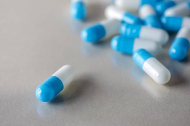 Mavi arka plan üzerinde birçok ilaç mavi ve beyaz kapsül