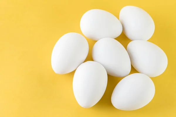 Siedem biały jaja kurze na białym tle na żółtym tle — Zdjęcie stockowe