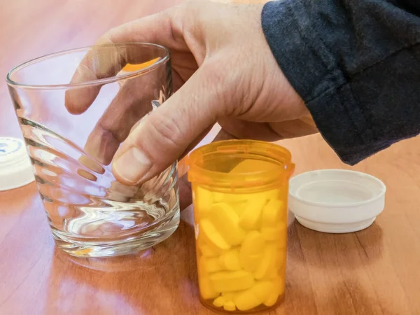 Person nahm ihre täglichen Medikamente mit einem Wasserglas ein — Stockfoto