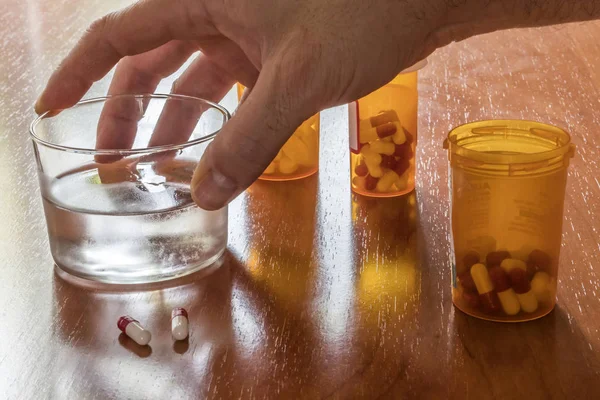 Persoon genomen zijn dagelijkse medicatie met een glas water — Stockfoto