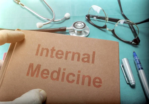 Doctor sostiene libro sobre medicina interna en un hospital — Foto de Stock