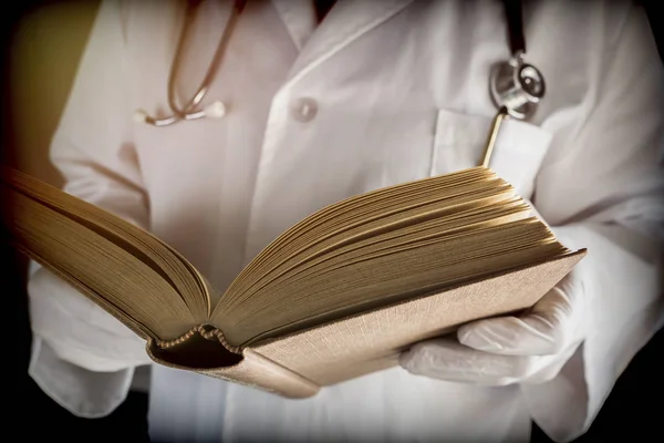 Doctor reads medical book in a hospital. Conceptual image