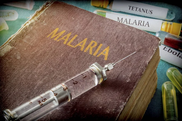 Vintage stříkačka na knize malárie, lékařská koncepce — Stock fotografie