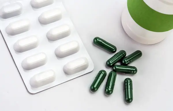 Beyaz arka plan üzerine açık bir şişe dökmek pills — Stok fotoğraf