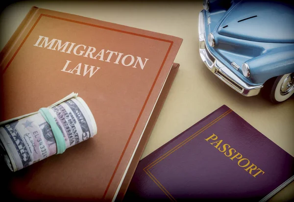 Bevándorlási törvény könyv mellett egy útlevél és kék miniatűr jármű, fogalmi kép — Stock Fotó