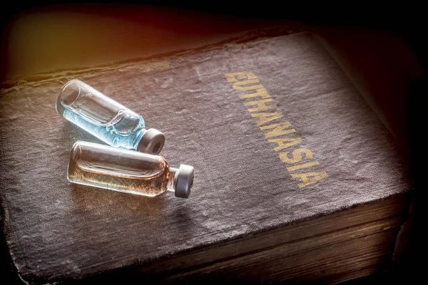 Two vials with medicine on an old book of euthanasia, conceptual image — Stock Photo, Image