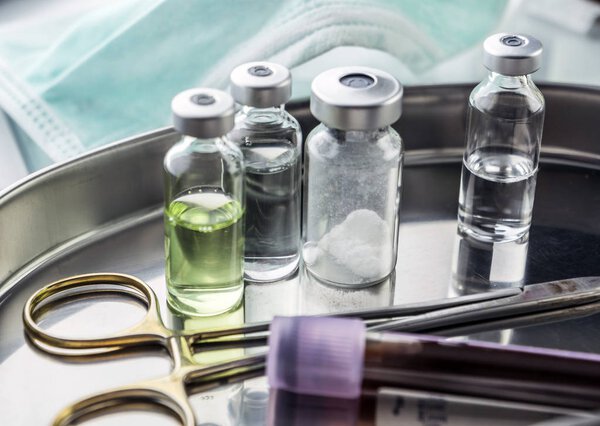 Ножницы и флаконы с образцами крови в подносе на столе шлюхи
