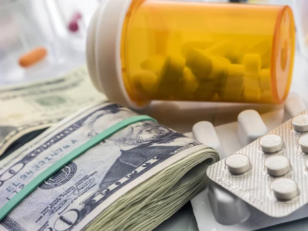 Some medicines next to a block of tickets of dollar, conceptual — Stock Photo, Image