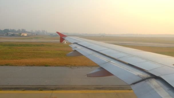 Самолет такси на взлетно-посадочной полосе в аэропорту утром, вид через окно — стоковое видео