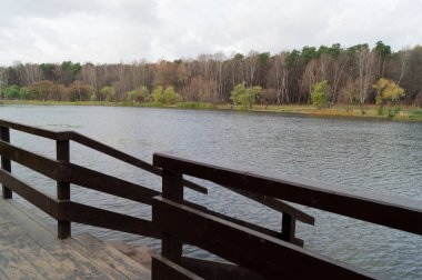Sonbahar ormanında ıssız bir göletin kenarında bir iskele.