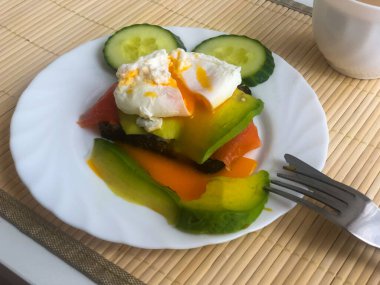 Beyaz tabakta kahve, siyah ekmek ve avokado ile haşlanmış yumurta.