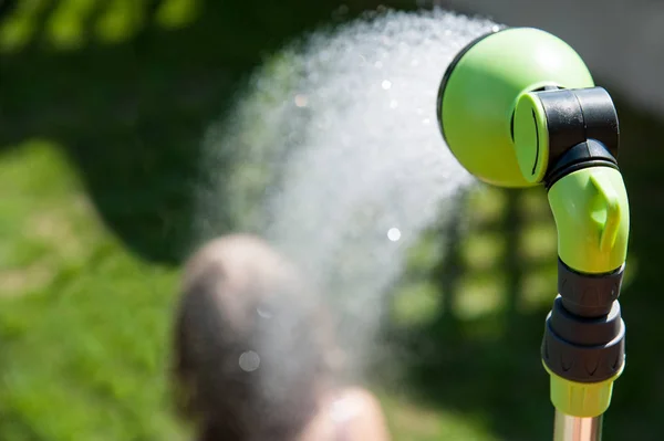 Das Mädchen duscht an einem heißen Sommertag im Garten — Stockfoto