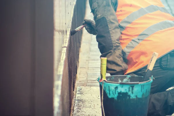 worker hand painting a gray wall, man working on the street (copy space on the left)